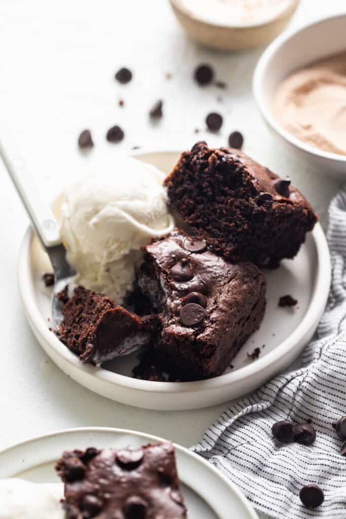 A plate of chocolate brownies with ice cream and a scoop of ice cream.