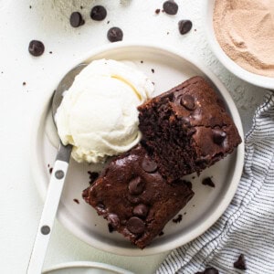 A plate of chocolate brownies with ice cream and whipped cream.