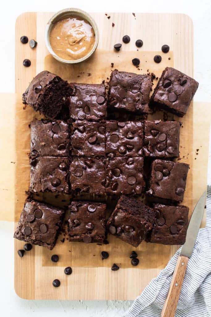 Chocolate brownies on a cutting board with peanut butter.