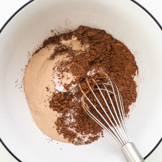 A bowl with cocoa powder and a whisk.