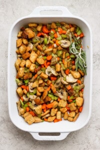 A white baking dish filled with stuffing and vegetables.