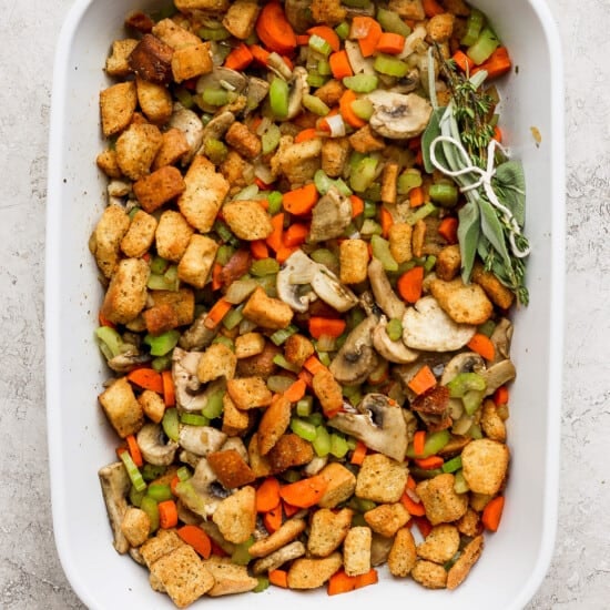 A white baking dish filled with stuffing and vegetables.