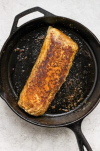 A piece of salmon in a cast iron skillet.