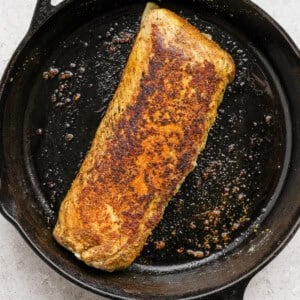 A piece of salmon in a cast iron skillet.