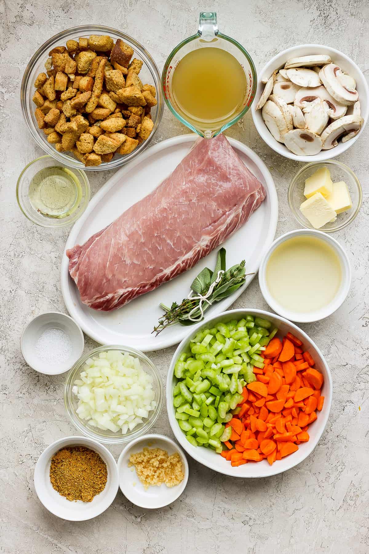 Ham, carrots, mushrooms and other ingredients in white bowls on a white background.