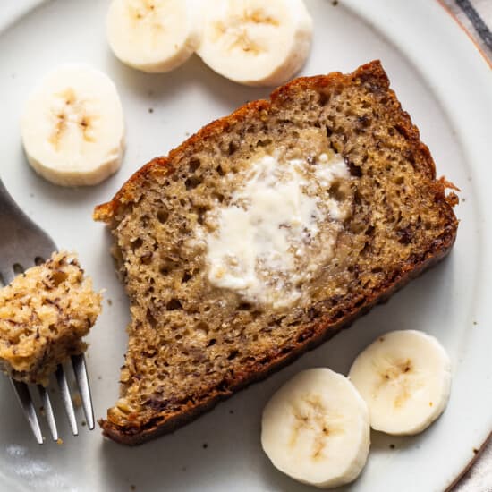 A slice of banana bread on a plate with a fork.