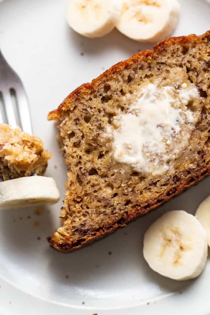 A slice of banana bread on a plate with a fork.