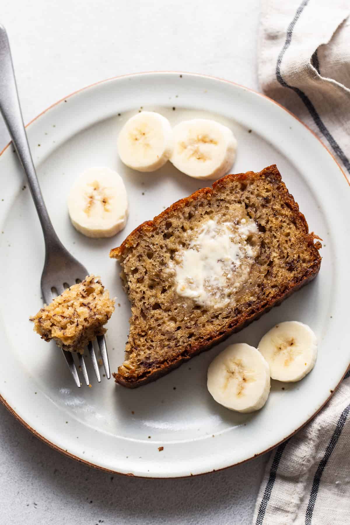 A slice of banana bread on a plate with a fork.