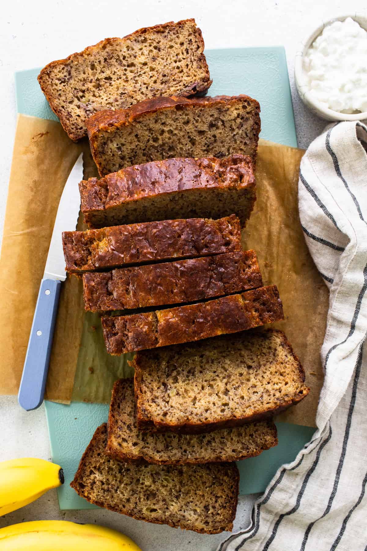 Sliced banana bread on a cutting board with a knife.