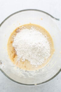 A glass bowl with flour and sugar in it.