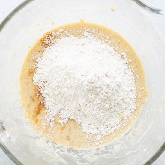 A glass bowl with flour and sugar in it.