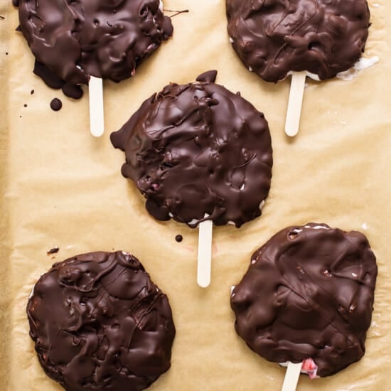 Chocolate covered popsicles on a baking sheet.