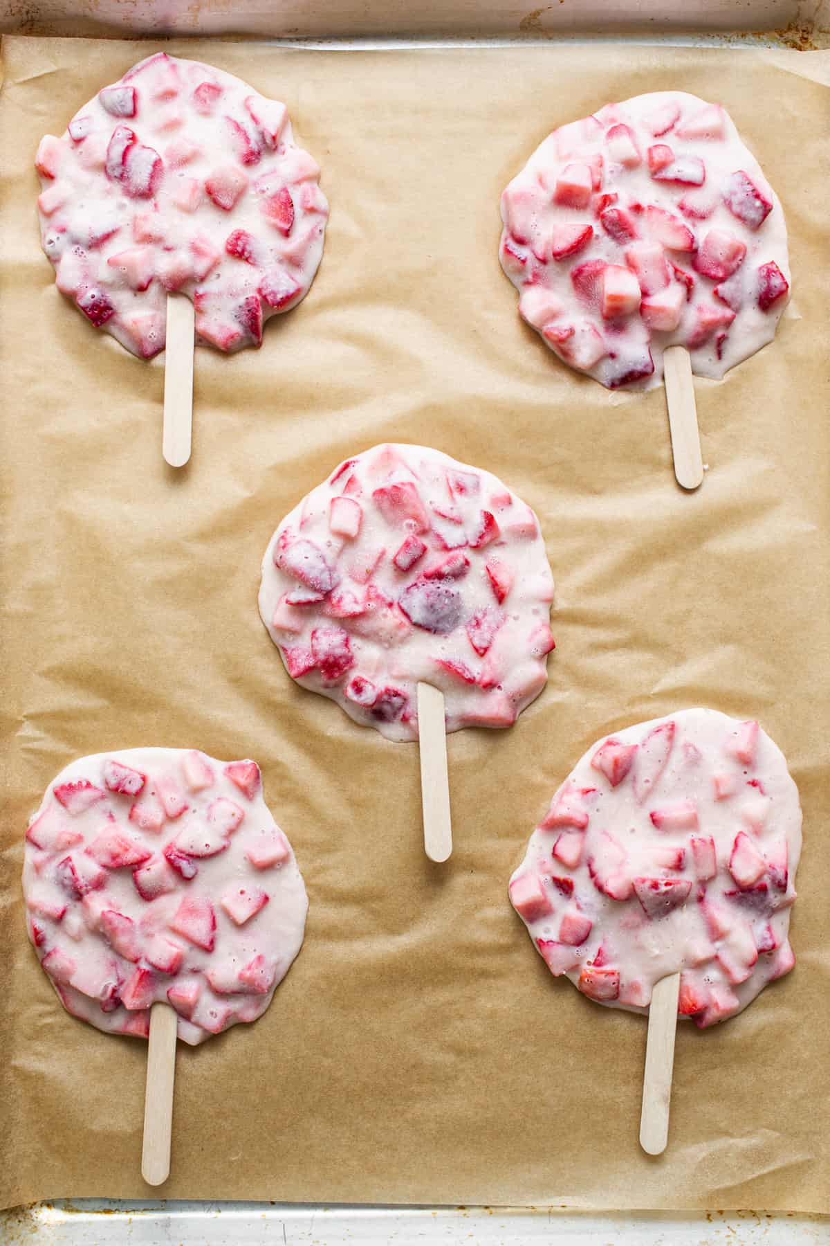 Strawberry popsicles on a baking sheet.