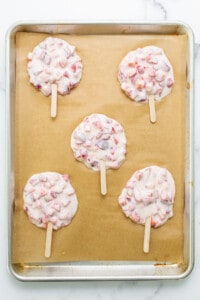 Strawberry popsicles on a baking sheet.