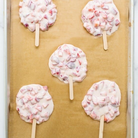 Strawberry popsicles on a baking sheet.