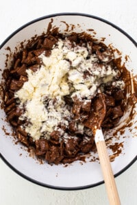 A bowl filled with chocolate and a wooden spoon.