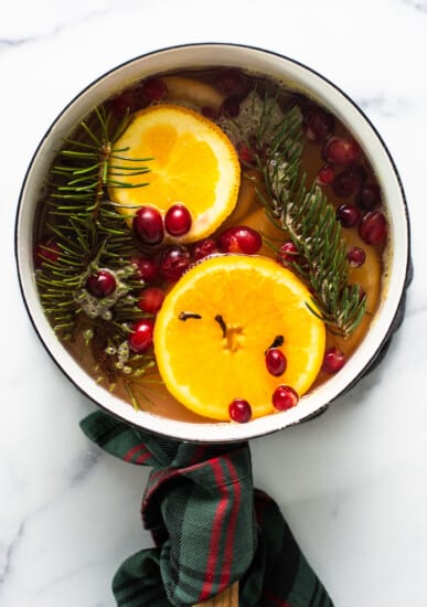 A pan with oranges, cranberries and sprigs of fir.
