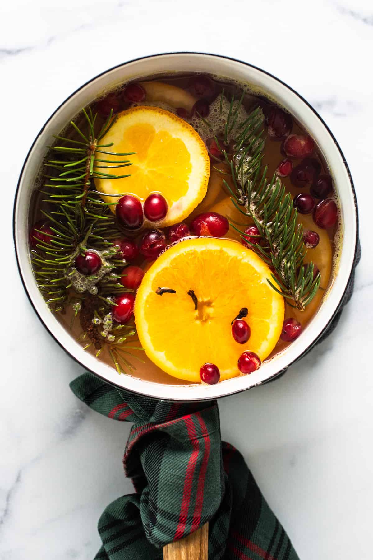 A pan with oranges, cranberries and sprigs of fir.