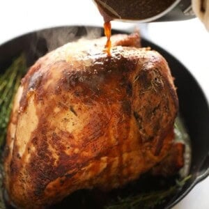 A person skillfully pours a flavorful sauce over a perfectly cooked sous vide turkey.