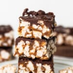 A stack of chocolate peanut butter fudge bars on a plate.
