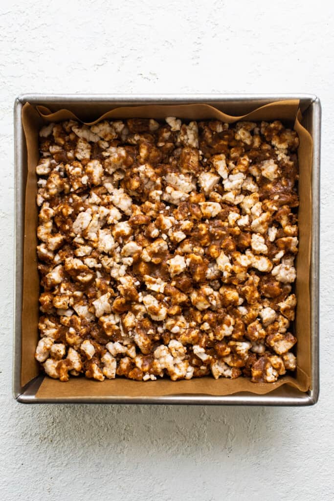 Caramel popcorn in a pan on a white surface.