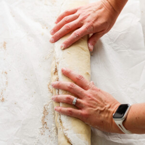 A woman's hands slicing a loaf of bread.