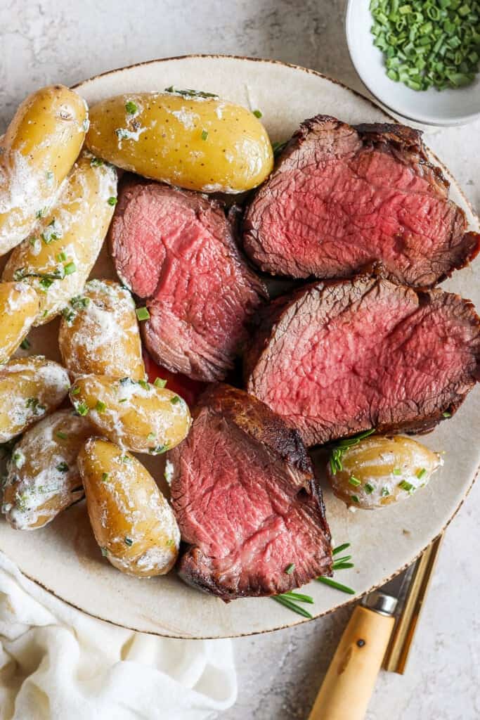 Steak and potatoes on a plate.