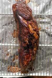 A piece of meat on a cooling rack.