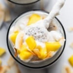 A bowl of mango and coconut yogurt with a spoon.
