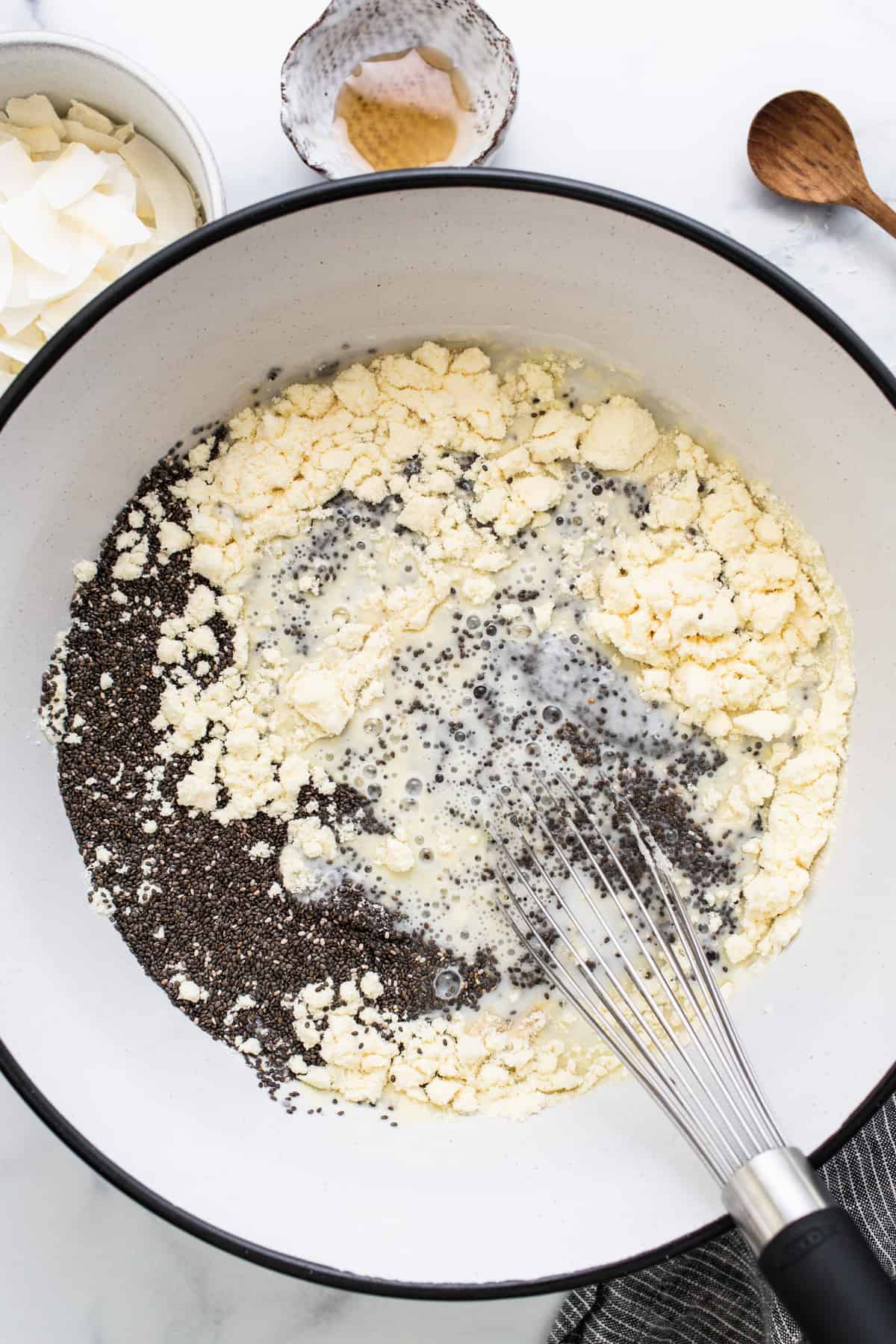 A bowl of ingredients in a pan with a wooden spoon.