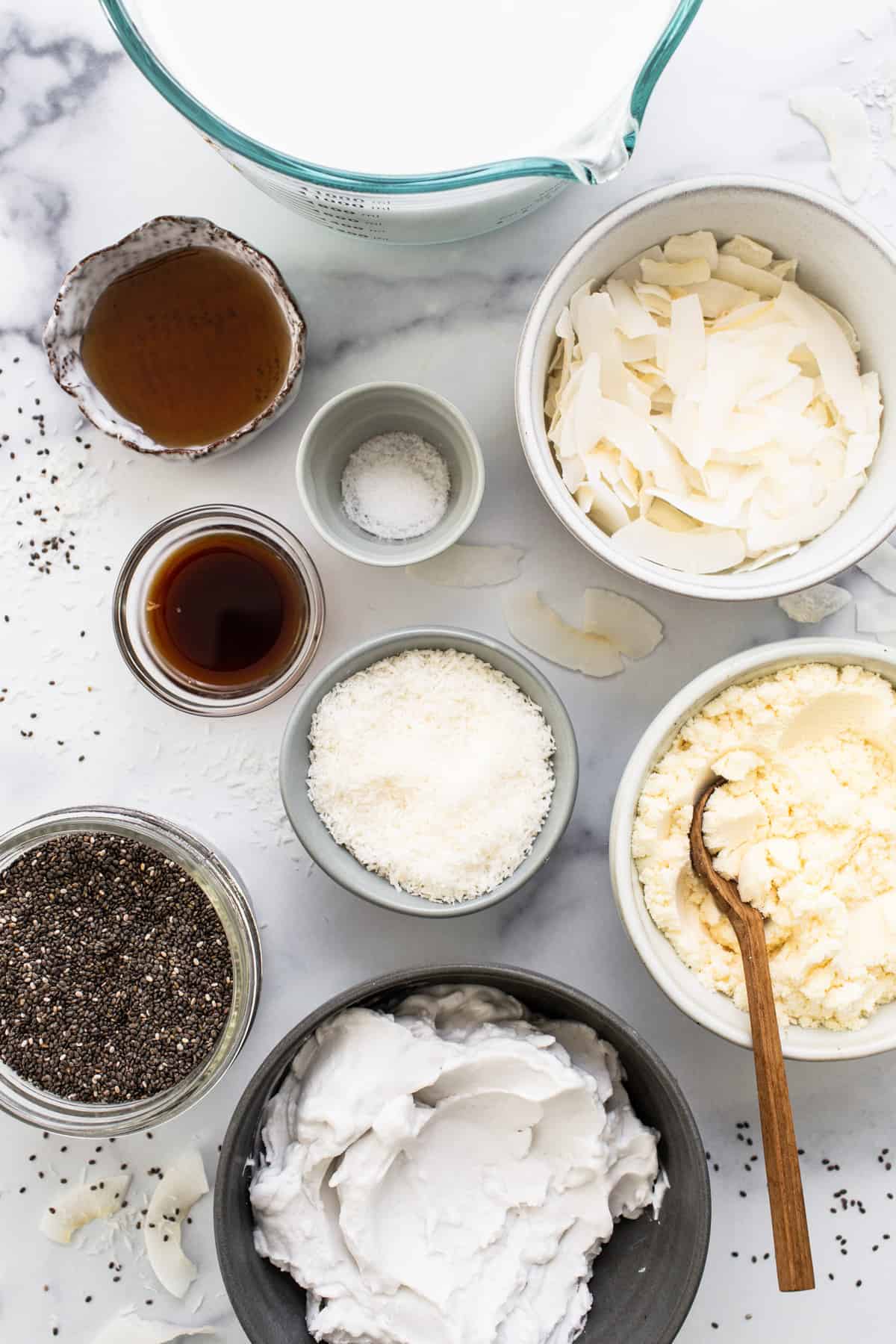 All the ingredients for a chia pudding in bowls on a marble table.