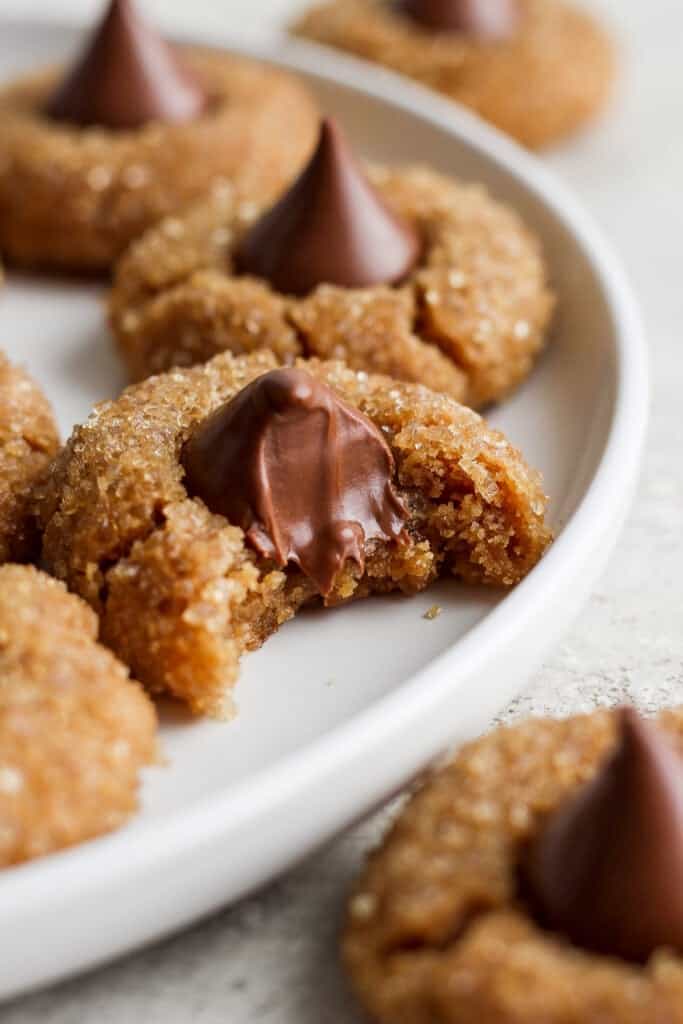 Peanut ،er cookies on a plate with a bite taken out of them.
