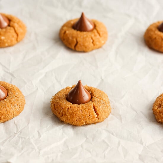 Peanut butter cookies with chocolate kisses on a baking sheet.