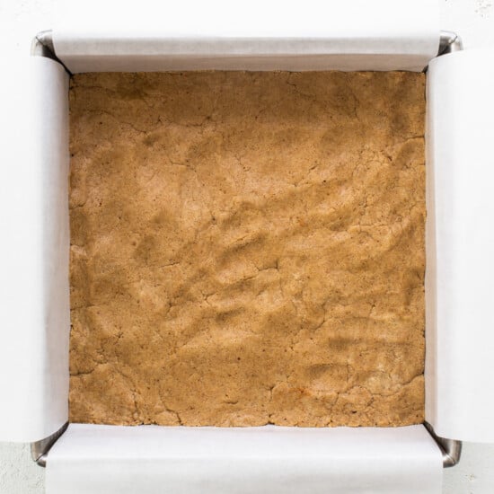 A brownie in a box on a white surface.