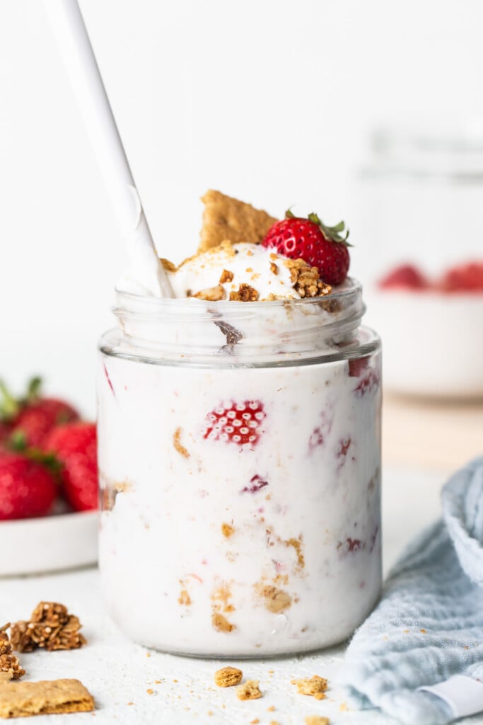 A jar of yogurt with strawberries and granola.