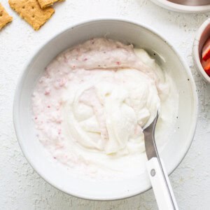 A bowl of yogurt with strawberries and crackers.