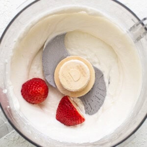 A food processor with whipped cream and strawberries.
