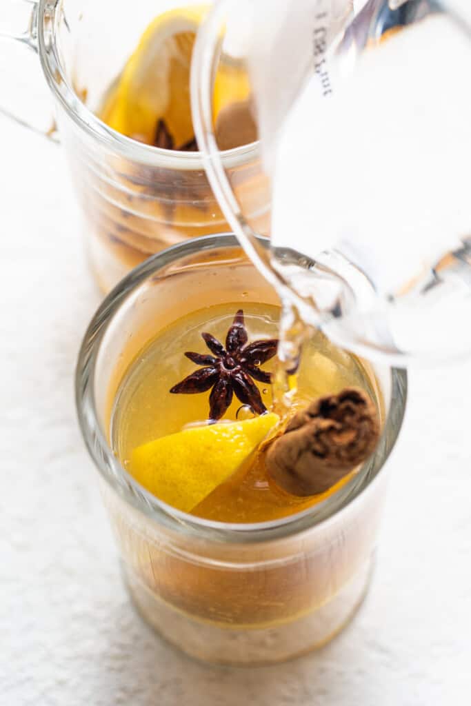 A glass with a lemon and star anise in it.