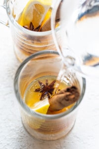 A glass of water with lemon and star anise in it.