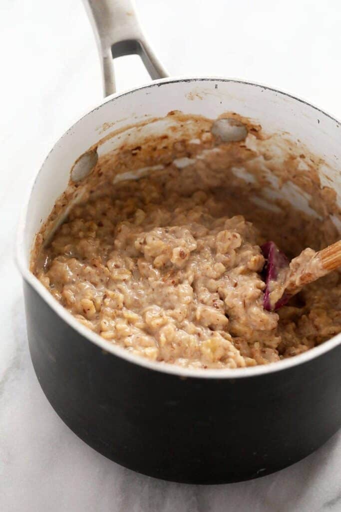 Oatmeal recipes featuring a tasty blend of oats, cooked to perfection in a pan and stirred with a wooden spoon.