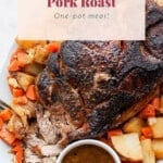 Baked pork roast served with carrots and potatoes on a plate.