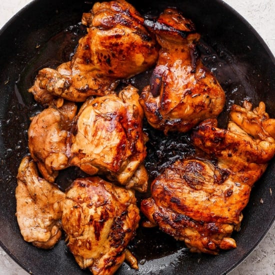 Grilled chicken in a skillet on a white background.