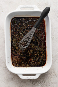 A bowl of brown liquid with a whisk.