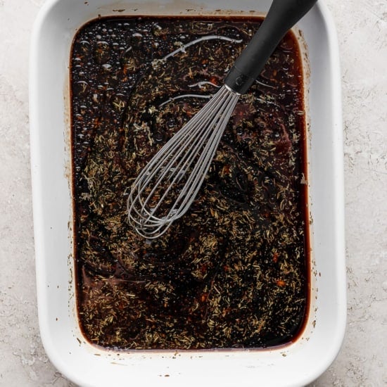 A bowl of brown liquid with a whisk.