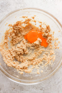 A bowl filled with a mixture of flour and an egg.