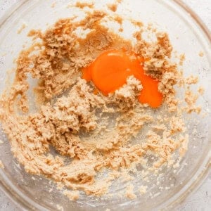 A bowl filled with a mixture of flour and an egg.