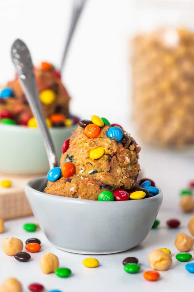 A bowl filled with m&m's and a spoon.