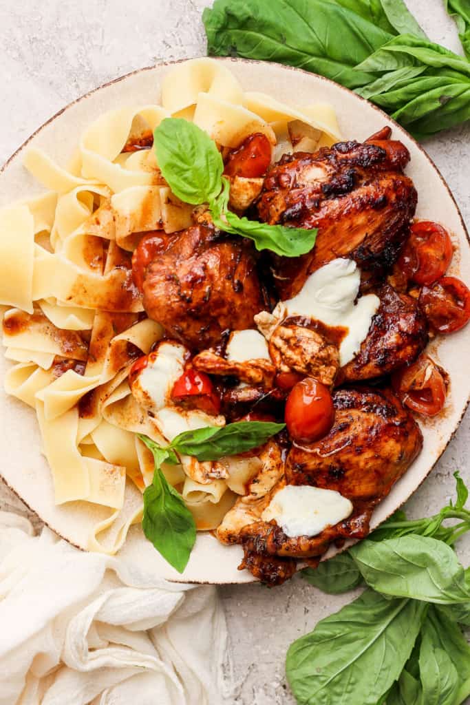 A plate of pasta with chicken, tomatoes and basil.