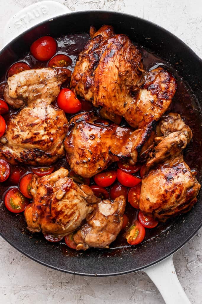 Grilled chicken in a skillet with tomatoes.