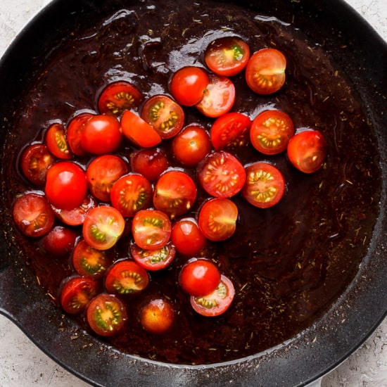 A frying pan with tomatoes in it.